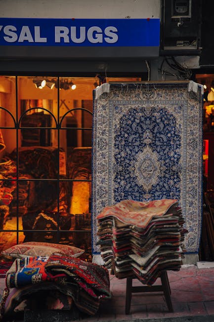 Close-up view of a colorful, patterned rug with intricate geometric and floral motifs, partially rolled back to reveal a light wooden floor beneath. The rug features shades of red, blue, yellow, and cream, with fringed edges along one side. The surface appears clean and well-maintained, reflecting good cleaning and restoration. Sunlight from a nearby window illuminates the scene, highlighting the texture and vibrant colors of the rug. This image exemplifies surface cleaning and deep cleaning techniques that Balham Carpet Cleaning offers for domestic and commercial spaces, ensuring hygiene and preservation of valuable textiles in a residential setting.